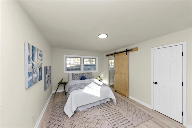 bedroom with a barn door and light hardwood / wood-style floors