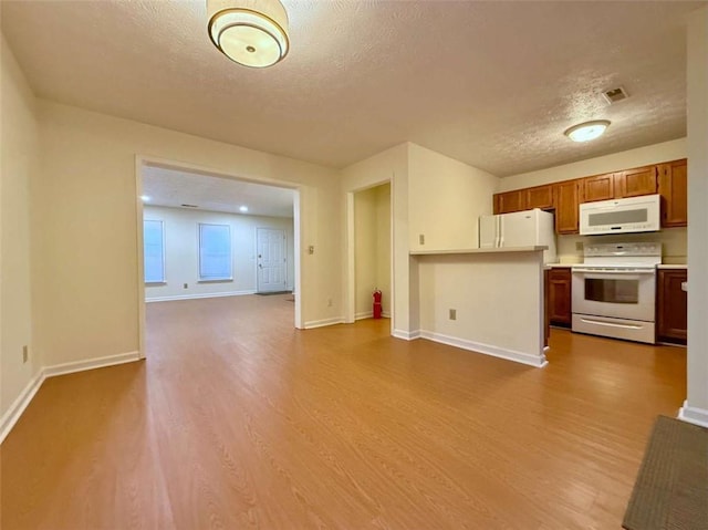 3533 Mulberry Way, Duluth, GA 30096 - kitchen with white appliances, a textured ceiling, open floor plan, wood finished floors, and light countertops