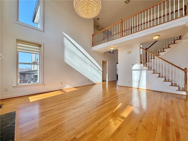 6765 Crofton Dr, Alpharetta, GA 30005 - unfurnished living room with stairway, a high ceiling, wood finished floors, baseboards, and a chandelier