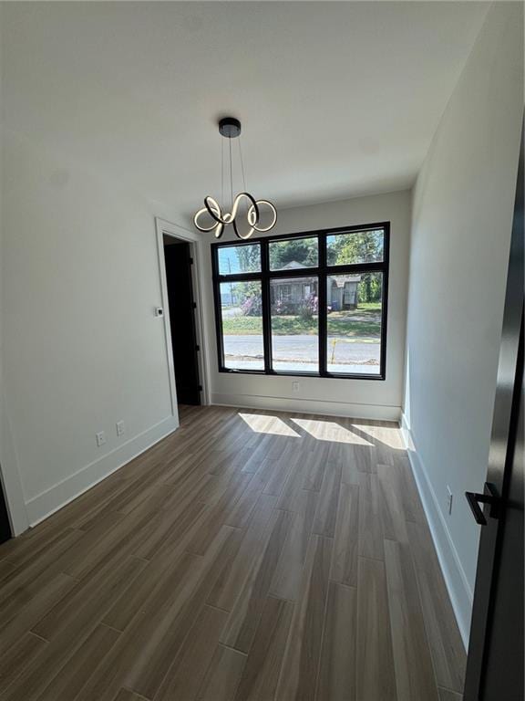 3960 Clairmont Rd Unit 2, Chamblee, GA 30341 - unfurnished dining area featuring a chandelier, dark wood-type flooring, and baseboards