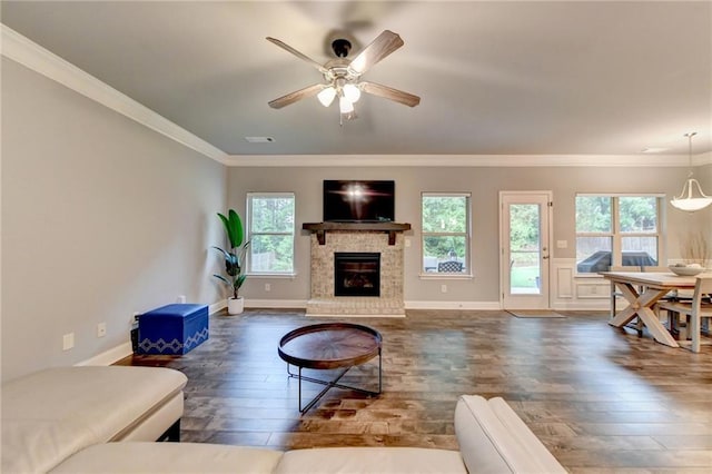 living area with hardwood / wood-style floors, plenty of natural light, ornamental molding, a brick fireplace, and a ceiling fan