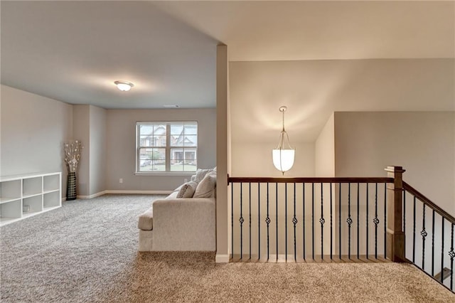 hall with carpet, baseboards, and an upstairs landing