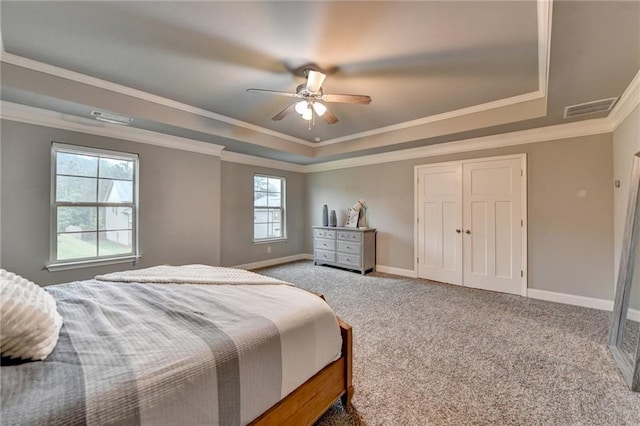 carpeted bedroom featuring a raised ceiling, ornamental molding, baseboards, and a ceiling fan