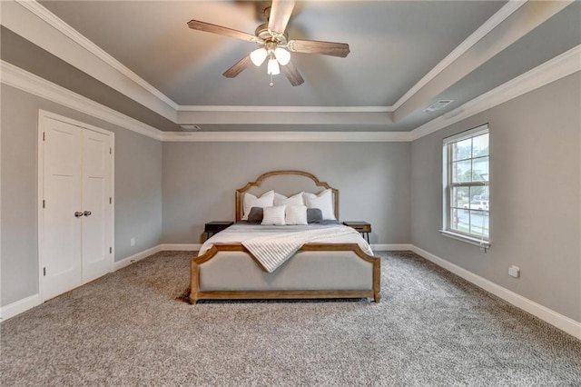 carpeted bedroom featuring a tray ceiling, baseboards, ornamental molding, and a ceiling fan