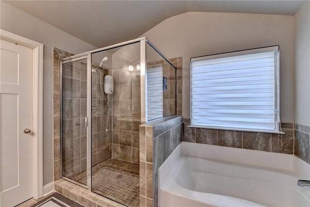bathroom with a shower stall, a bath, and vaulted ceiling