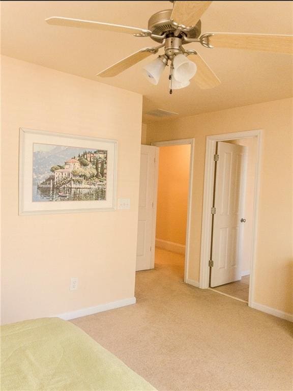 unfurnished bedroom featuring baseboards, a ceiling fan, and light colored carpet