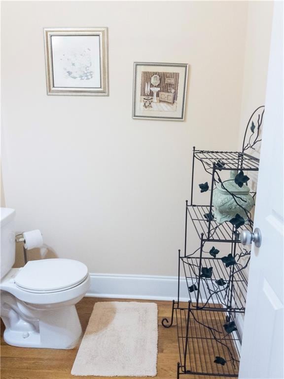 bathroom with wood finished floors, toilet, and baseboards