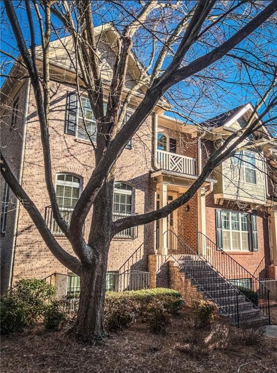 view of property exterior featuring brick siding and a balcony