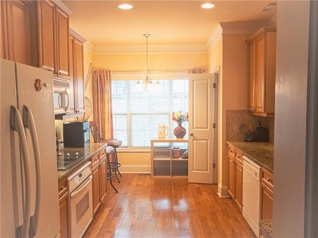 kitchen featuring white appliances, wood finished floors, backsplash, dark stone counters, and crown molding