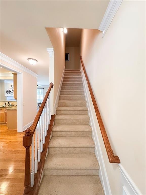 stairway featuring ornamental molding, wood finished floors, and baseboards