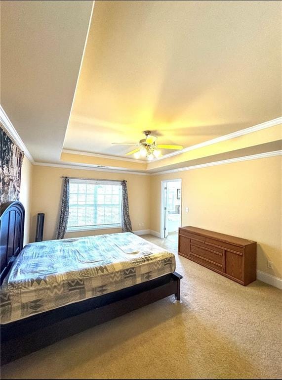 bedroom featuring ornamental molding, a tray ceiling, light colored carpet, and baseboards