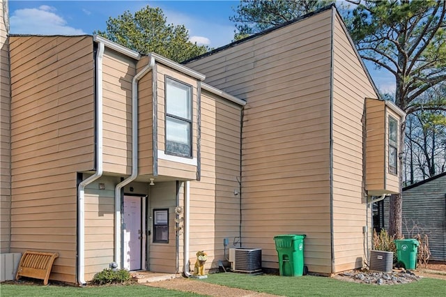 rear view of house featuring a lawn and central air condition unit