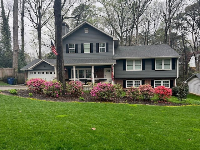 tri-level home featuring a garage, a porch, and a front lawn