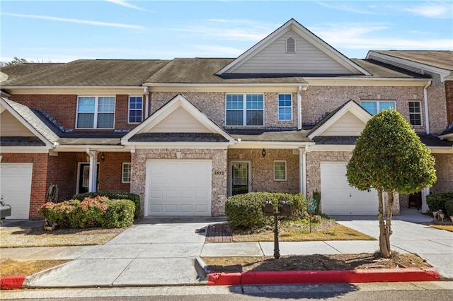 townhome / multi-family property with a garage, concrete driveway, and brick siding