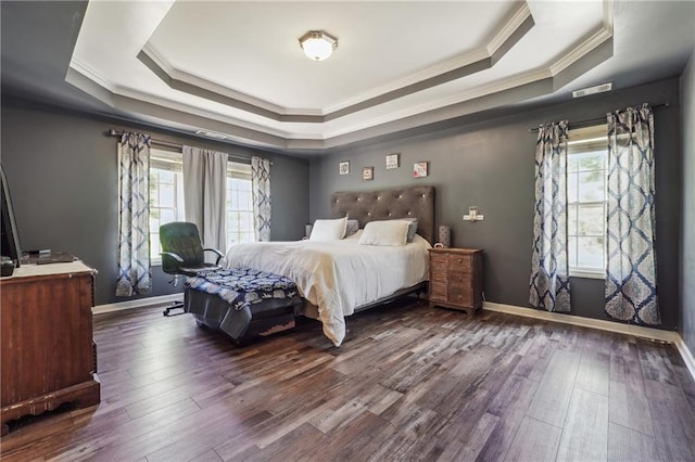 bedroom with ornamental molding, a raised ceiling, multiple windows, and wood finished floors