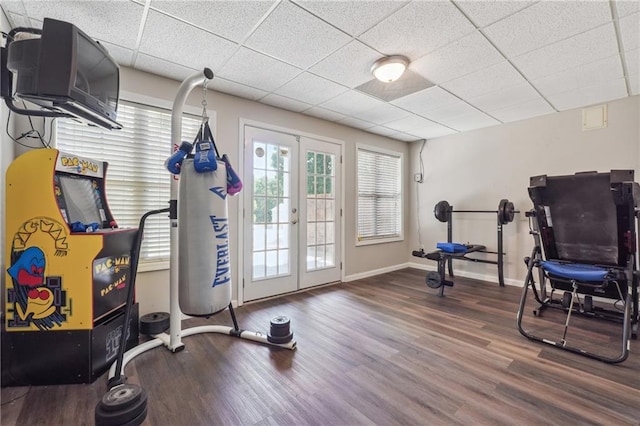 exercise room with french doors, wood finished floors, a paneled ceiling, and baseboards