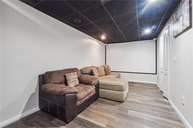 home theater room with wood finished floors, baseboards, a paneled ceiling, and recessed lighting