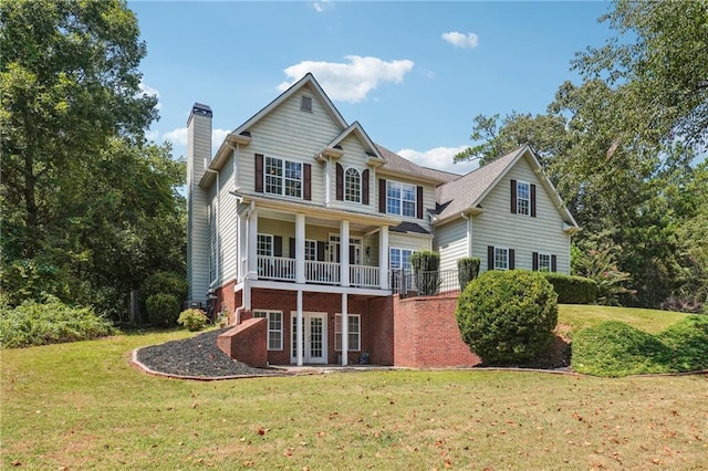 back of house with a chimney, a yard, and brick siding