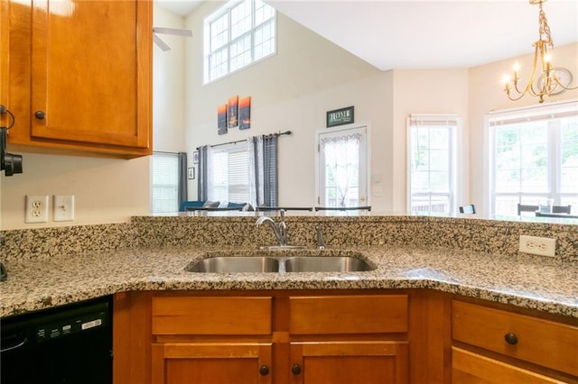 kitchen featuring dishwasher, a sink, a chandelier, brown cabinetry, and light stone countertops