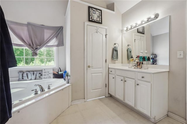 bathroom featuring vanity, a garden tub, vaulted ceiling, and baseboards