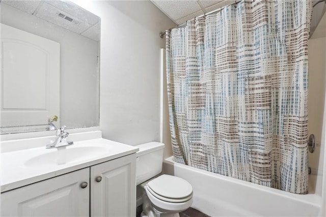 bathroom featuring a paneled ceiling, toilet, shower / tub combo with curtain, and vanity
