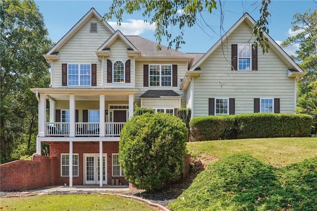 view of front of property with french doors, a front yard, brick siding, and a patio area