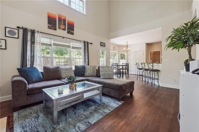 living area with wood finished floors, a chandelier, baseboards, and a towering ceiling