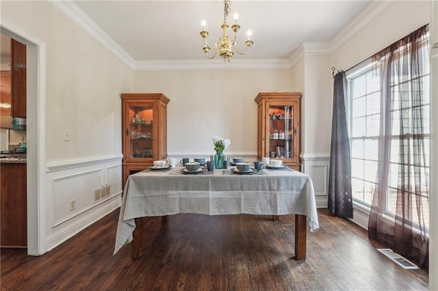 dining area featuring a chandelier, ornamental molding, dark wood-type flooring, a wainscoted wall, and a decorative wall