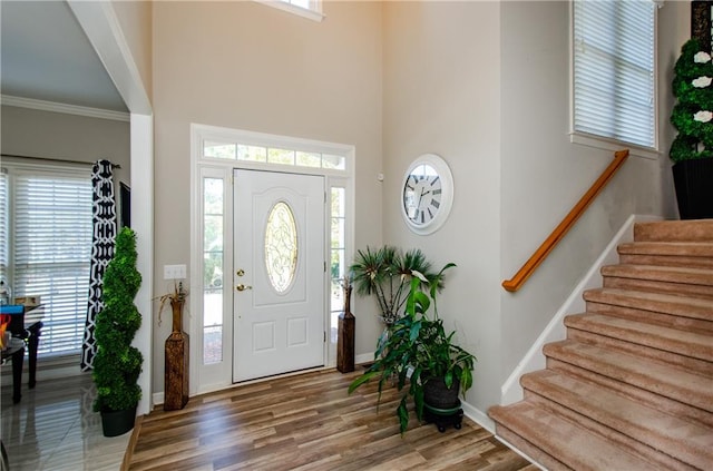 entrance foyer featuring crown molding, a healthy amount of sunlight, and hardwood / wood-style flooring