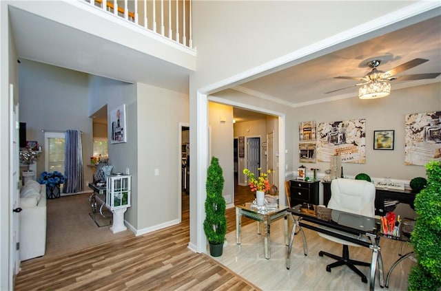 office featuring crown molding, hardwood / wood-style flooring, a high ceiling, and ceiling fan