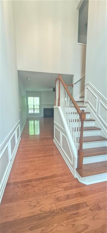 2061 Fosco Dr, Duluth, GA 30097 - stairs with a decorative wall, a high ceiling, a fireplace, wood finished floors, and wainscoting