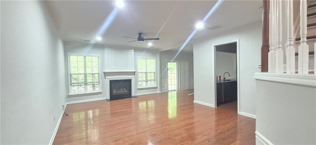 2061 Fosco Dr, Duluth, GA 30097 - unfurnished living room with a ceiling fan, a fireplace with flush hearth, wood finished floors, baseboards, and a sink
