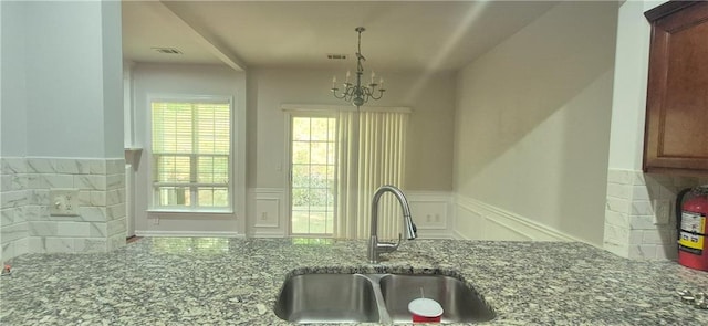 2061 Fosco Dr, Duluth, GA 30097 - kitchen with a sink, a chandelier, dark stone countertops, wainscoting, and decorative light fixtures