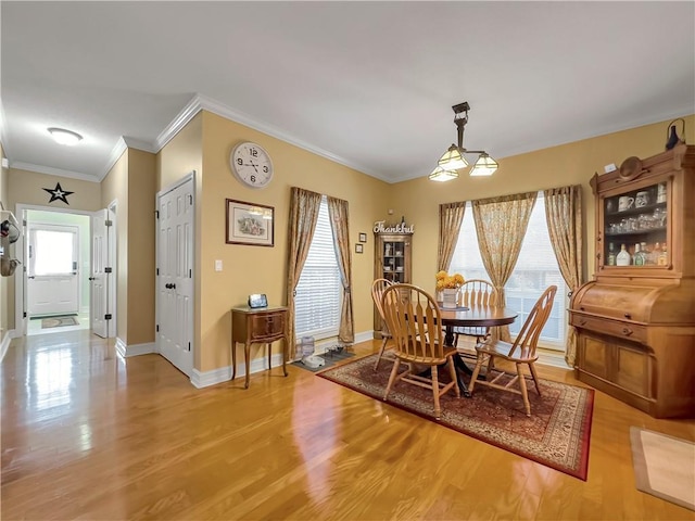 dining area featuring crown molding, baseboards, and wood finished floors