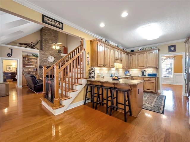 kitchen with light stone counters, a breakfast bar, light wood-style flooring, and crown molding