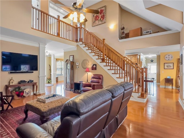 living room with crown molding, stairway, a wealth of natural light, and ornate columns