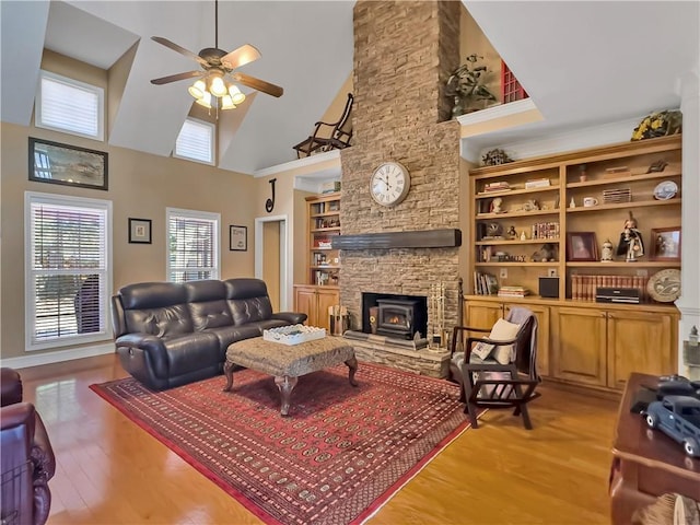 living room featuring light wood-style floors, ceiling fan, a high ceiling, and built in features