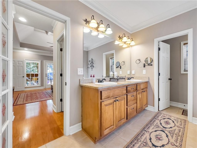 bathroom featuring double vanity, ornamental molding, a sink, and baseboards