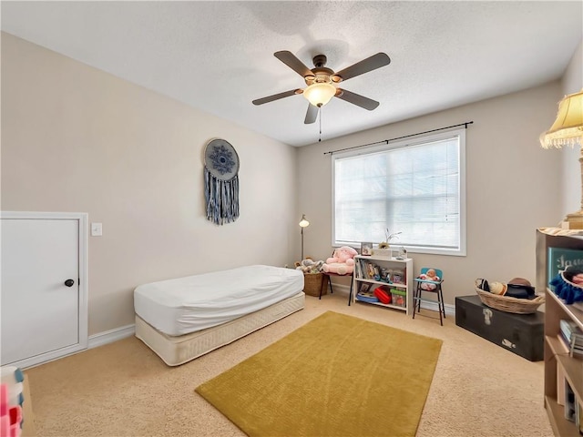 carpeted bedroom with a ceiling fan, a textured ceiling, and baseboards