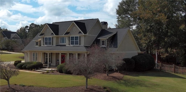 view of front of home featuring a porch, a chimney, a front yard, and fence