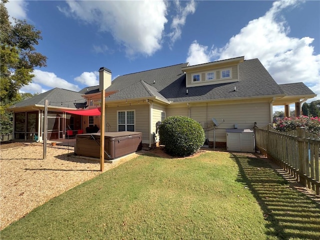 rear view of house featuring a hot tub, a shingled roof, a sunroom, fence, and a yard