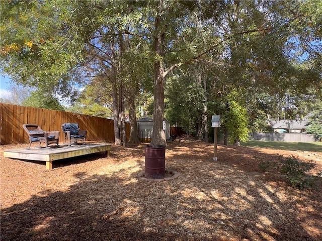 view of yard with a fenced backyard, an outdoor structure, a deck, and a shed