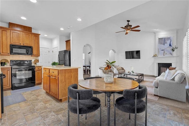 dining area with arched walkways, baseboards, ceiling fan, a fireplace, and recessed lighting