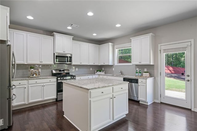 kitchen with white cabinets, a center island, stainless steel appliances, backsplash, and visible vents