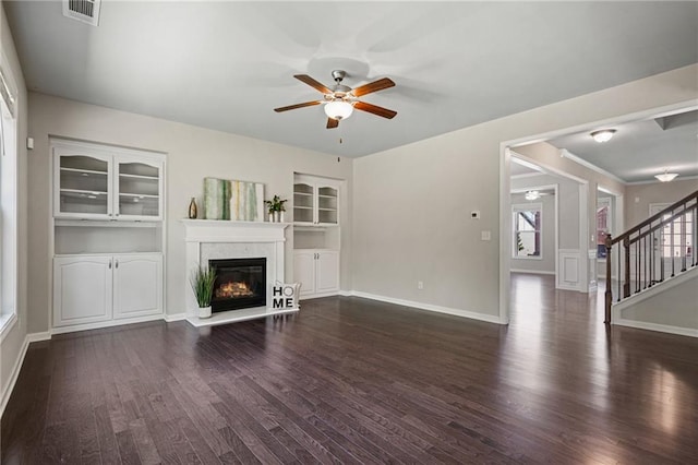 unfurnished living room with visible vents, a ceiling fan, dark wood-style flooring, and a high end fireplace