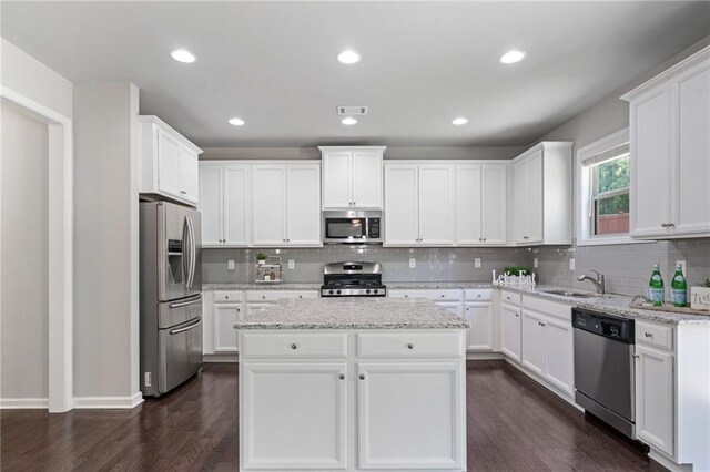 kitchen featuring decorative backsplash, a kitchen island, a sink, dark wood-style floors, and stainless steel appliances