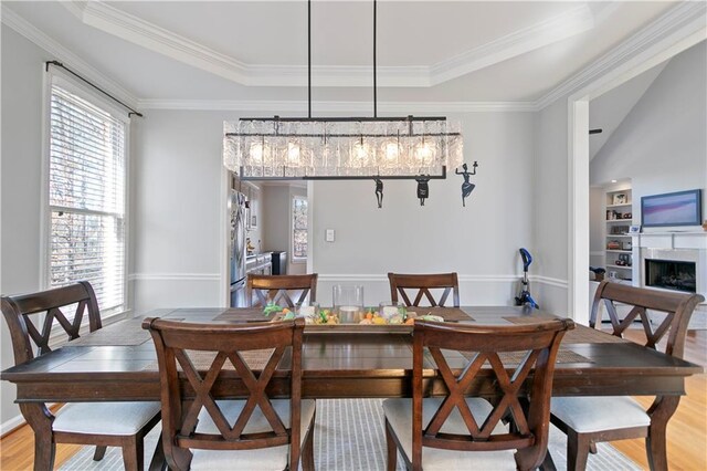 325 Stonecastle Pass, South Fulton, GA 30331 - dining space featuring a tray ceiling, crown molding, built in shelves, a fireplace, and light wood-type flooring