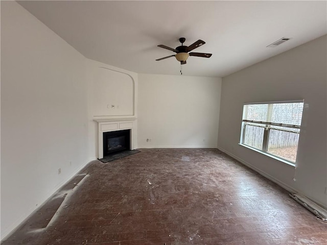 unfurnished living room featuring a ceiling fan, a fireplace, visible vents, and baseboards