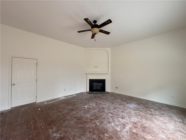 unfurnished living room with a ceiling fan, a glass covered fireplace, dark wood-style flooring, and baseboards