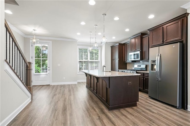 3657 Atherton Park Ct, Suwanee, GA 30024 - kitchen featuring appliances with stainless steel finishes, ornamental molding, dark brown cabinets, light wood-type flooring, and a center island with sink